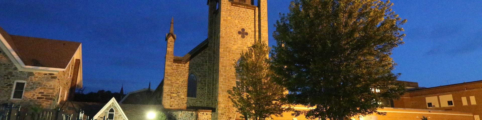 A church with a tall spire and a clock tower at dusk.