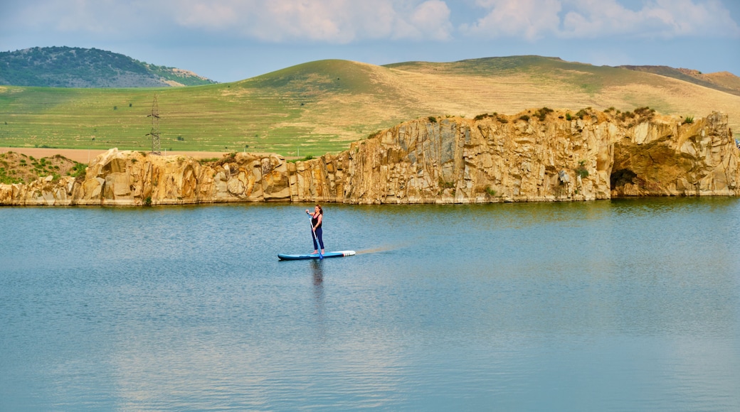 Young female tourist paddle-boarding on an isolated lake, with space for text at the bottom. Iacobdeal lake in Turcoaia, Tulcea, Romania at sunset, with warm light.