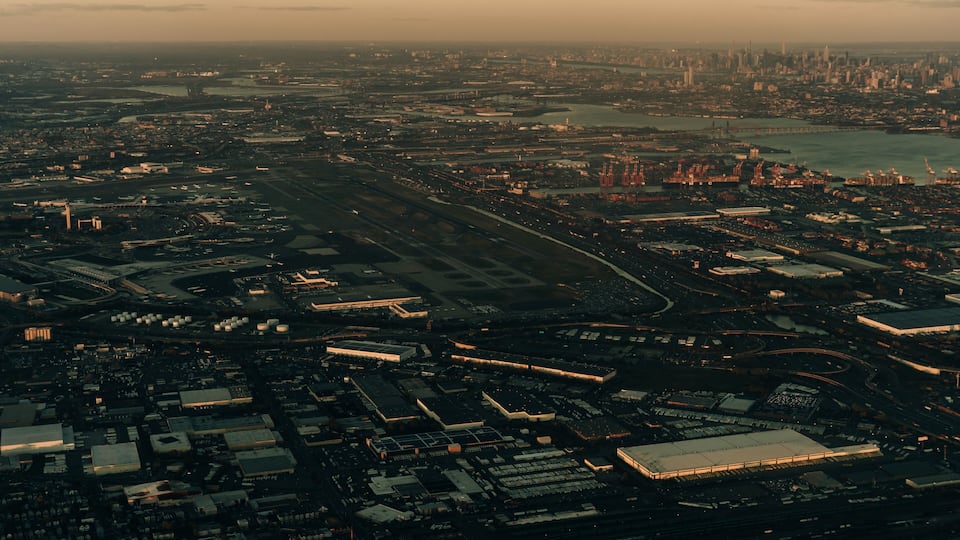 An aerial view of a city with a large airport, industrial area, and a river.