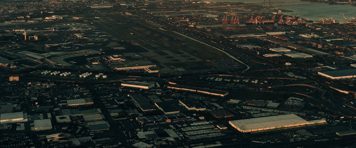 An aerial view of a city with a large airport, industrial area, and a river.