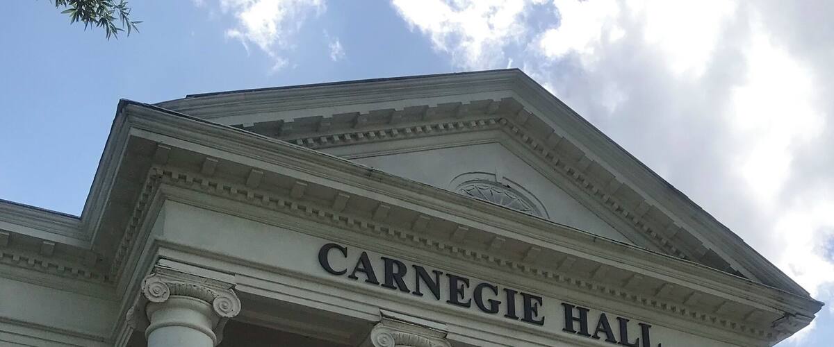 Carnegie Hall's facade with columns and the name 'CARNEGIE HALL' above.