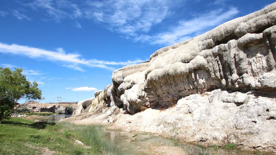 A river flowing through a rocky landscape with a bridge in the distance.