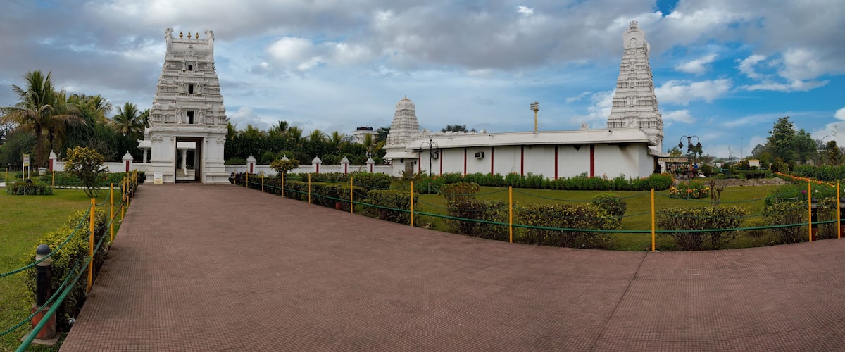 A temple complex with two prominent towers, a paved pathway, and a surrounding garden.