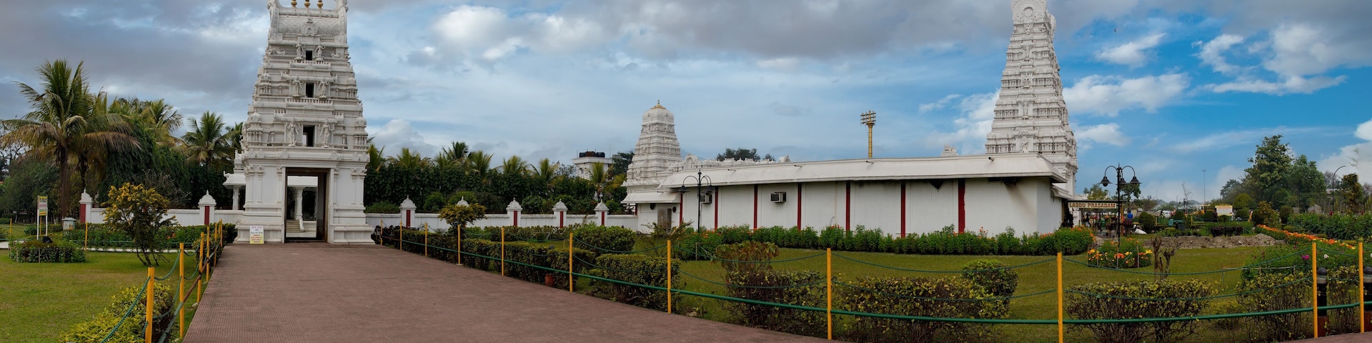 A temple complex with two prominent towers, a paved pathway, and a surrounding garden.