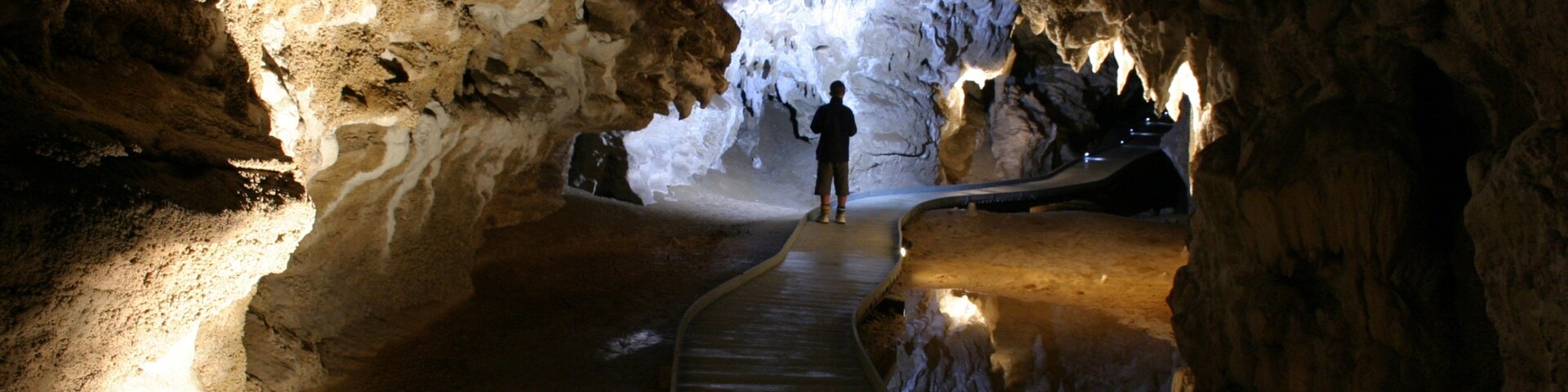 Una cueva con un pasillo de madera que conduce a una abertura luminosa.