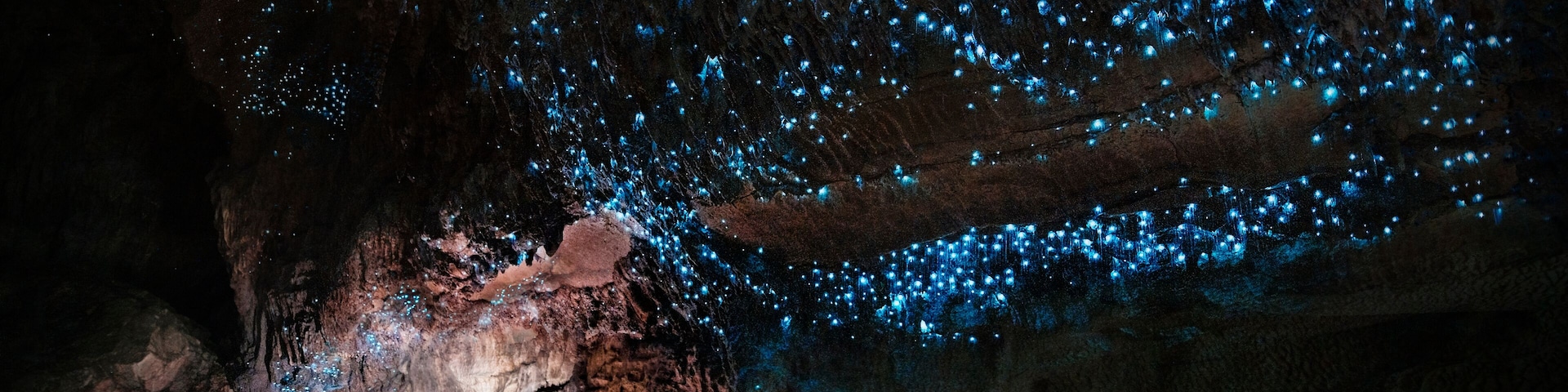 Dos personas caminando por una cueva con luces azules bioluminiscentes.