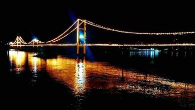 Uma ponte à noite com luzes refletindo na água.