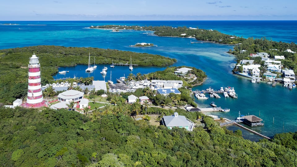 A lighthouse, marina, and tropical island landscape.