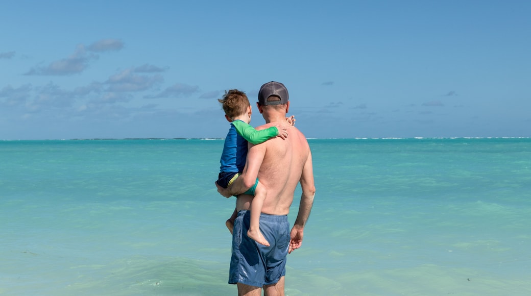 Father carries young son into the blue-green water of the Sea of Abaco