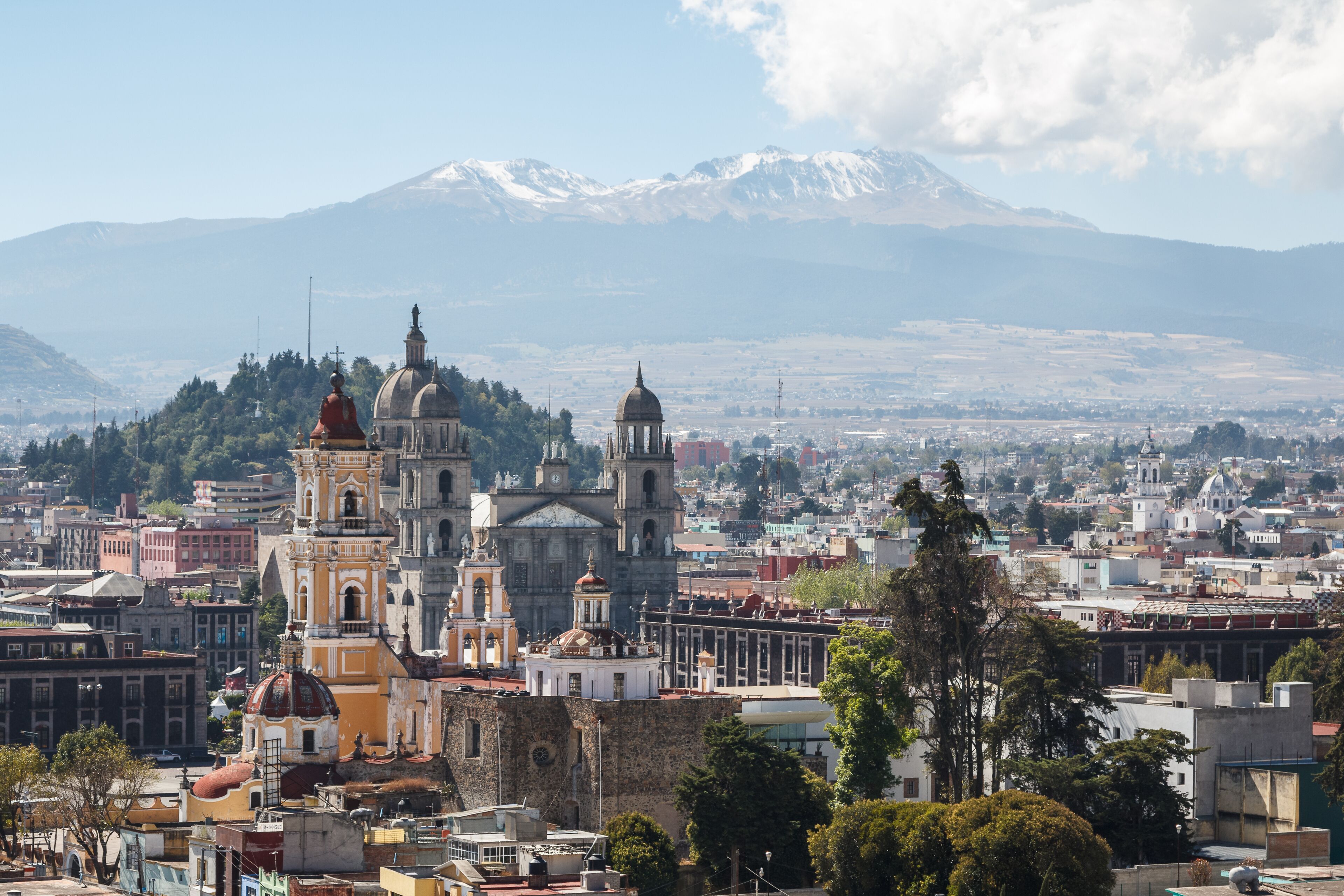 A cityscape with prominent historical buildings and a snow-capped mountain in the background.
