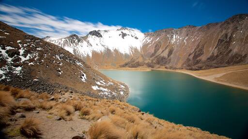 Un lago de montaña rodeado de terreno rocoso y picos nevados.