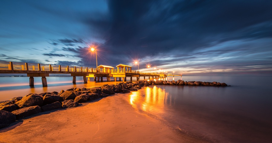 Un muelle largo que se adentra en aguas tranquilas al anochecer bajo un cielo despejado.