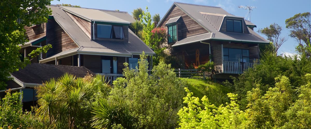 Two wooden houses with sloped roofs surrounded by lush greenery.