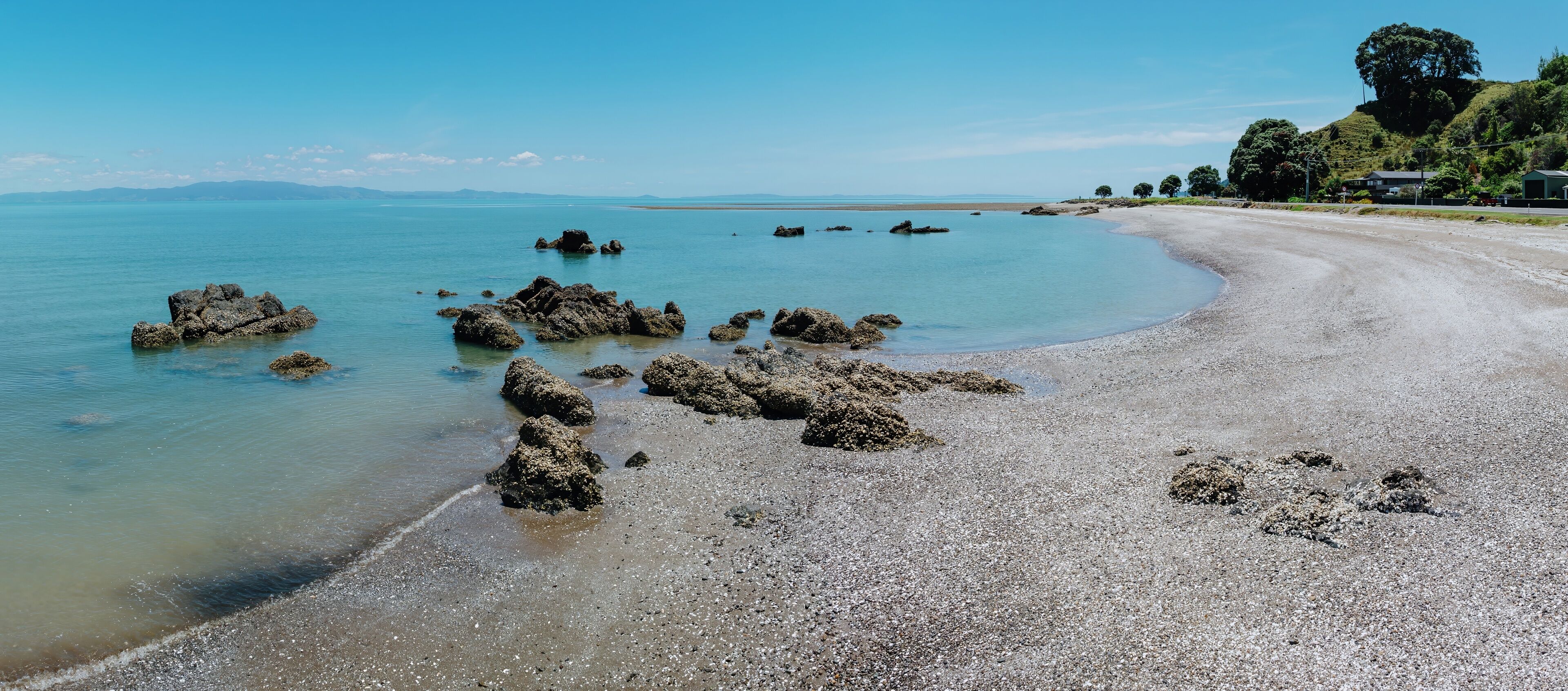 Tranquil beach scene with rocks and clear water. Sunny day at a coastal location. Perfect for relaxation. TE MATA, THAMES, COROMANDEL PENINSULA, NEW ZEALAND