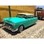 A turquoise vintage car parked on a cobblestone street.