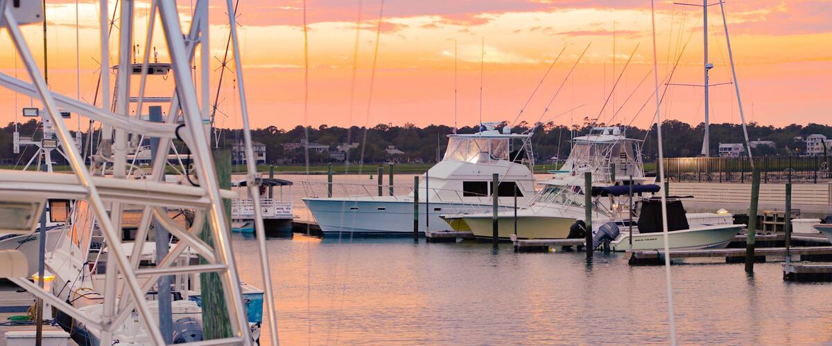 A marina with several boats docked at sunset.