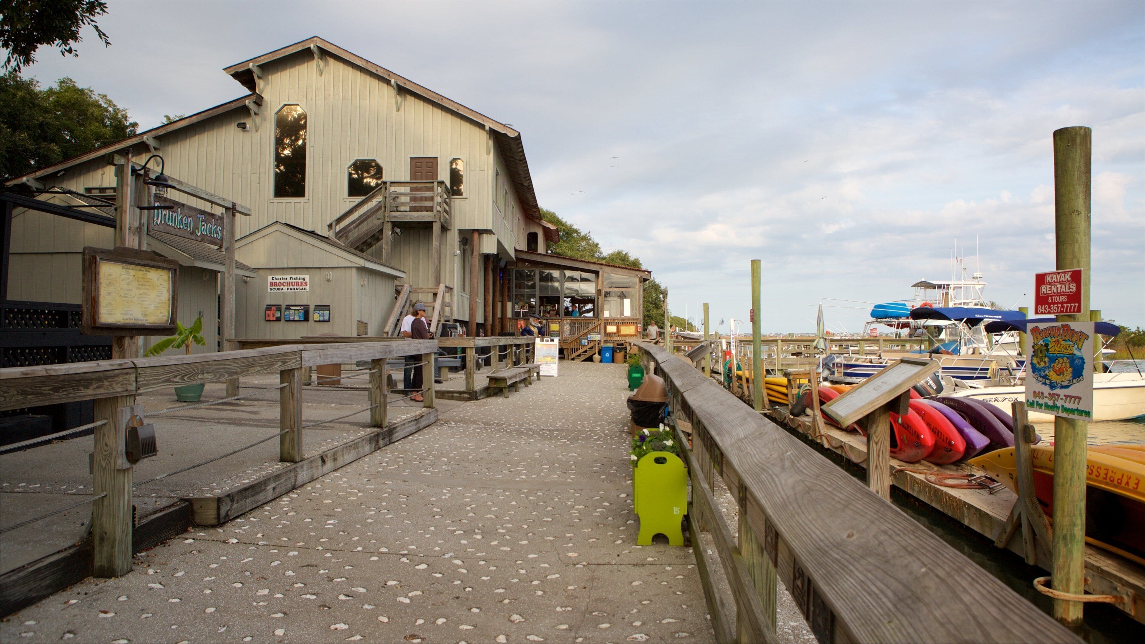A wooden pier leading to a building with signs for charter fishing and kayak rentals.