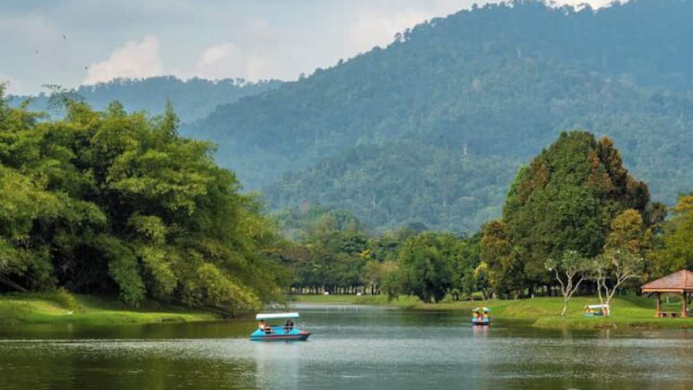 A calm lake with boats, surrounded by lush greenery and hills.