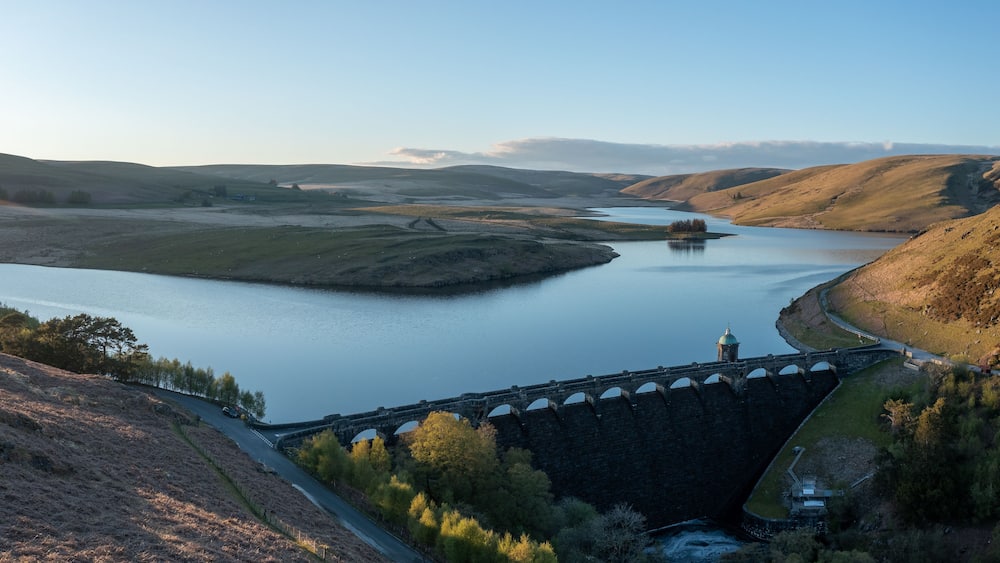 A river flowing through a valley with a bridge and a small island in the center.