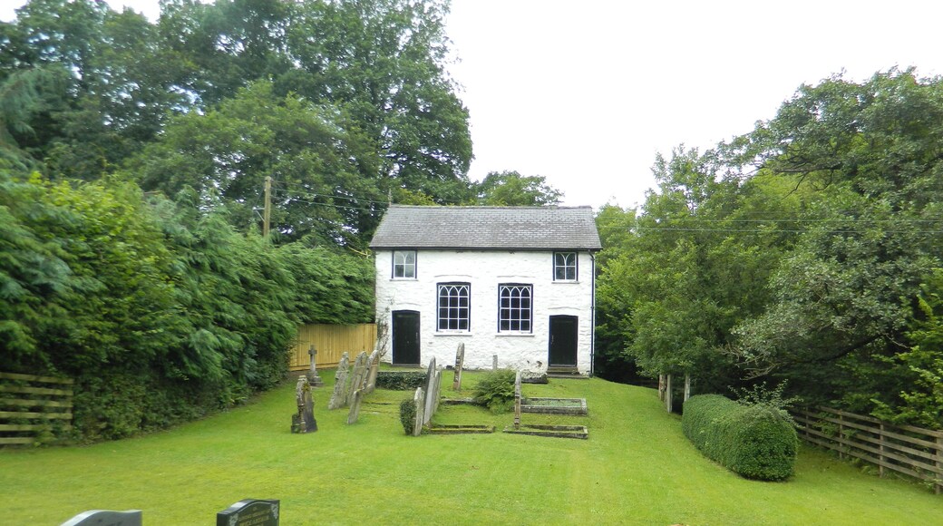 A white house with a black door and windows, surrounded by a well-maintained lawn and trees.