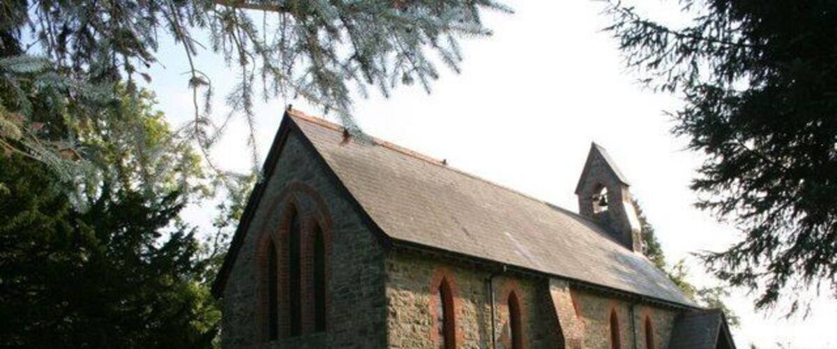 A stone church with a bell tower and arched windows.