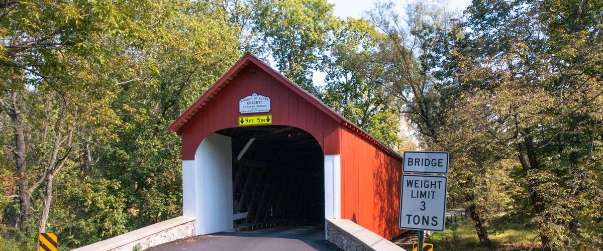 A covered bridge with a weight limit sign and a height restriction sign.