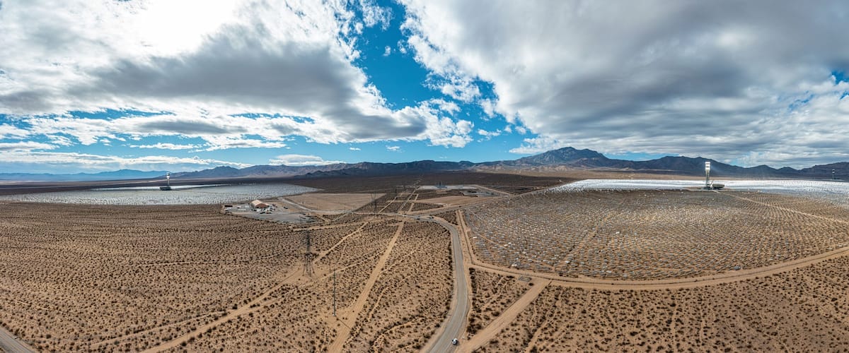 A vast desert landscape with mountains in the background, a large body of water, and a road leading through the area.