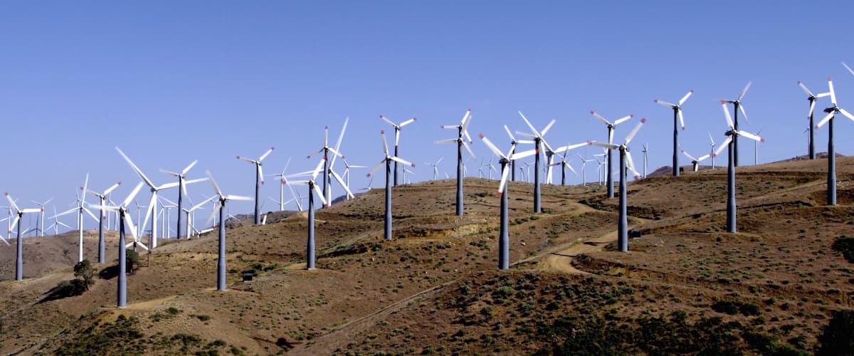 A wind farm with multiple wind turbines on a hilly landscape.