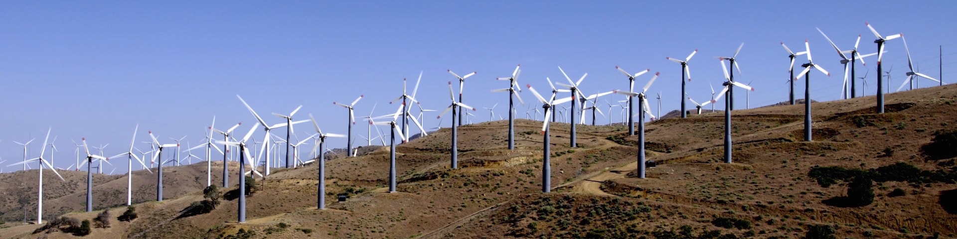 A wind farm with multiple wind turbines on a hilly landscape.
