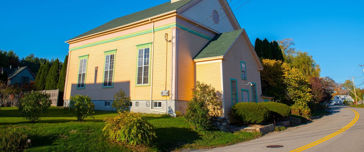 A yellow church with a green roof and a bell tower.