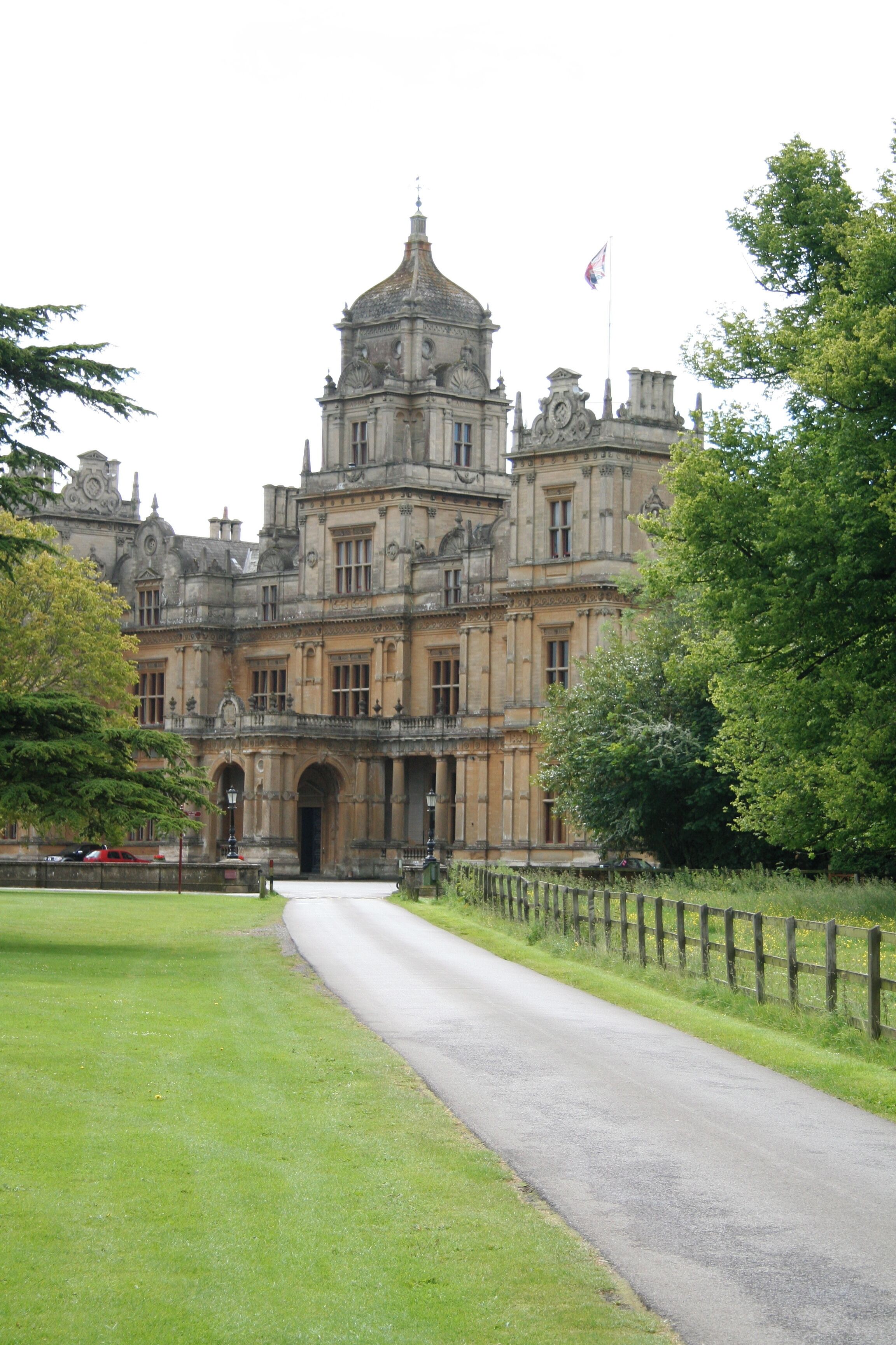 A historic building with a large central dome, surrounded by lush greenery and a paved pathway.