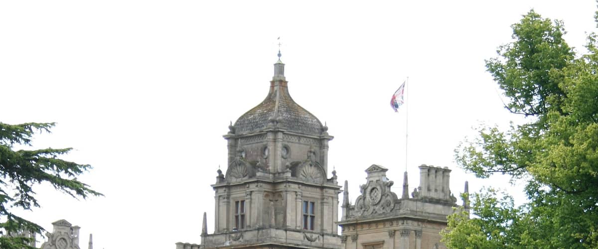 A historic building with a large central dome, surrounded by lush greenery and a paved pathway.