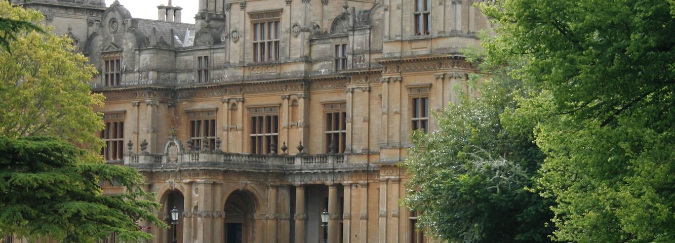 A historic building with a large central dome, surrounded by lush greenery and a paved pathway.