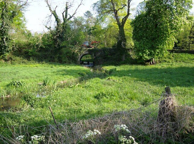 Stream through the edge of Avening The stream from Cherington Pond grows quickly and by the time it has reached Avening just over a mile away it is this big, with the obvious potential to flood much more in winter, judging by the flood plain and the size of the bridge. The minor road into Avening from the east crosses the stream on this bridge, being used by a tractor.