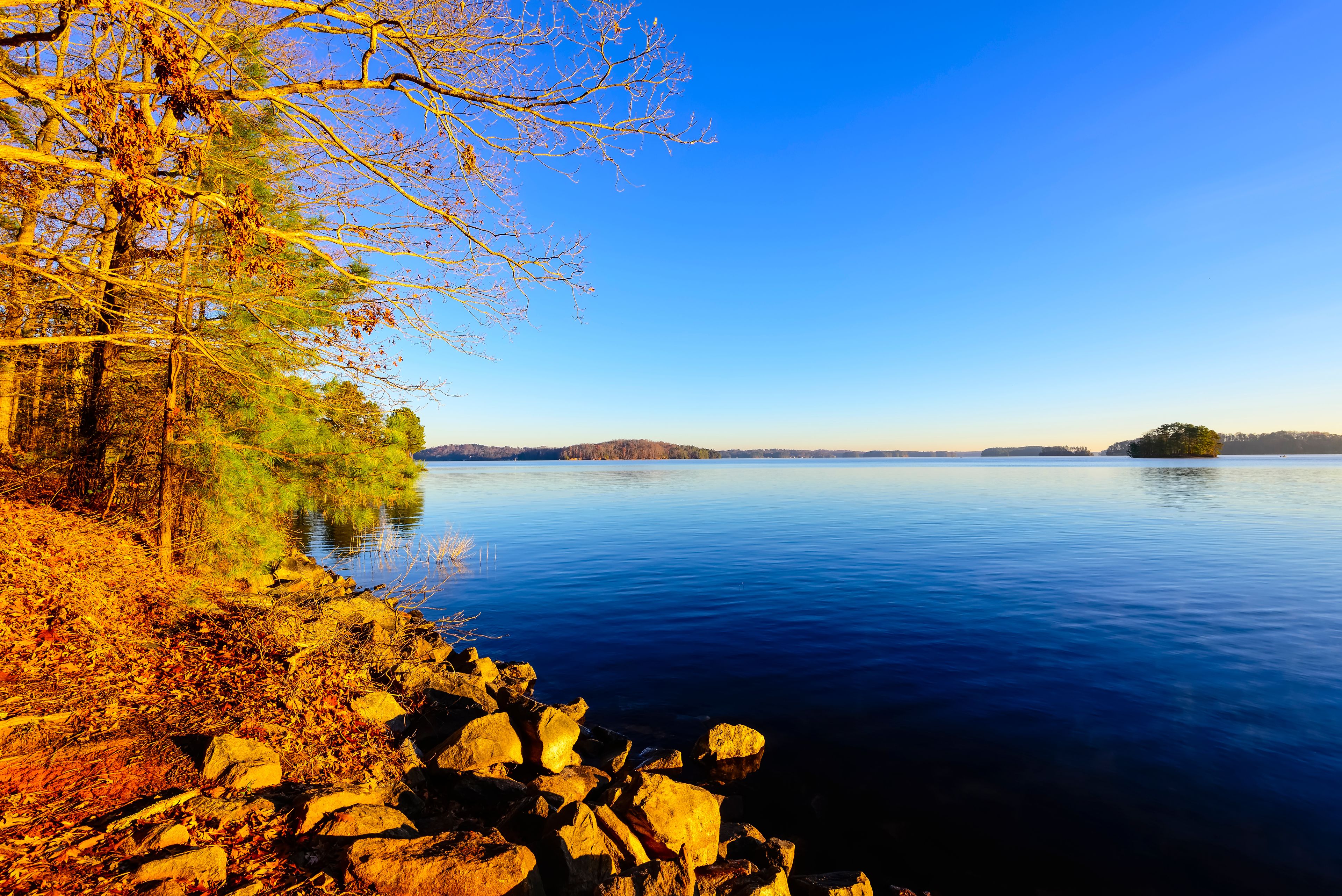 A calm lake with autumn foliage and rocky shores.