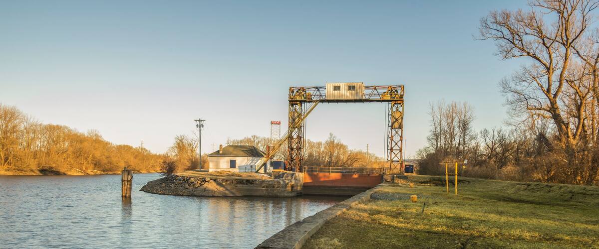A lock gate over a river with a small building beside it.