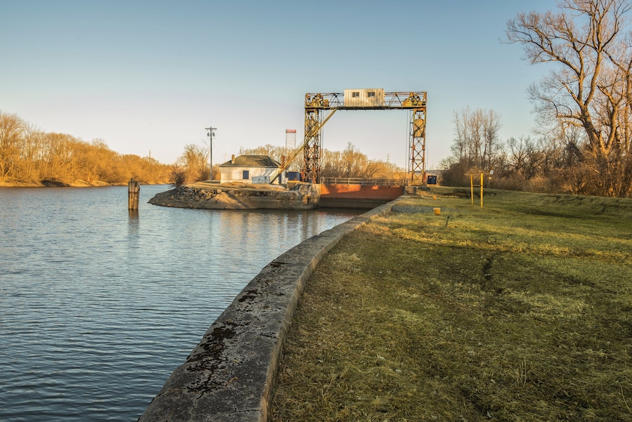 A lock gate over a river with a small building beside it.