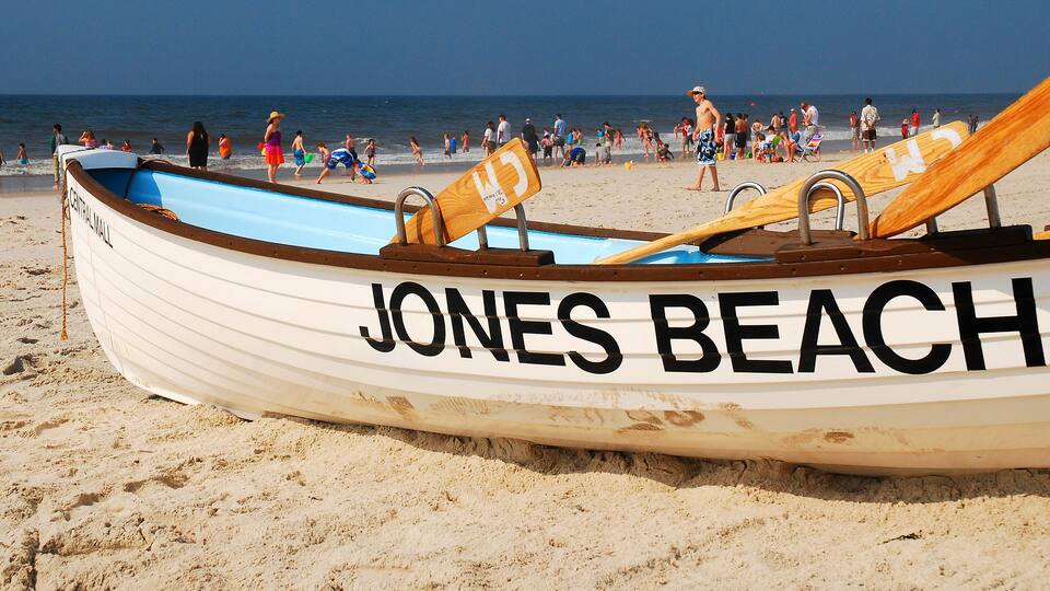 A beach with a rowboat labeled "JONES BEACH" and people walking along the shore.