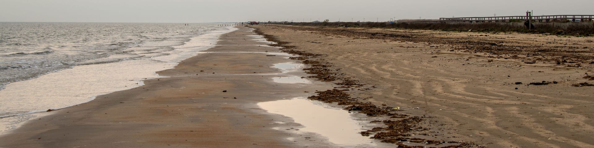 A beach with a wooden pier extending into the water.