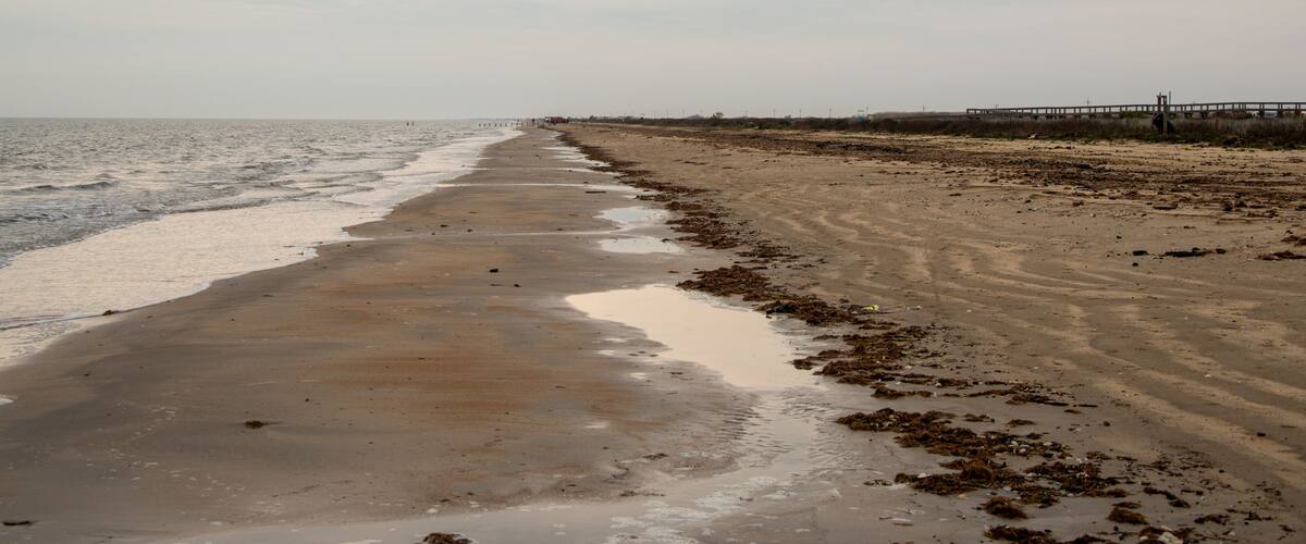 A beach with a wooden pier extending into the water.