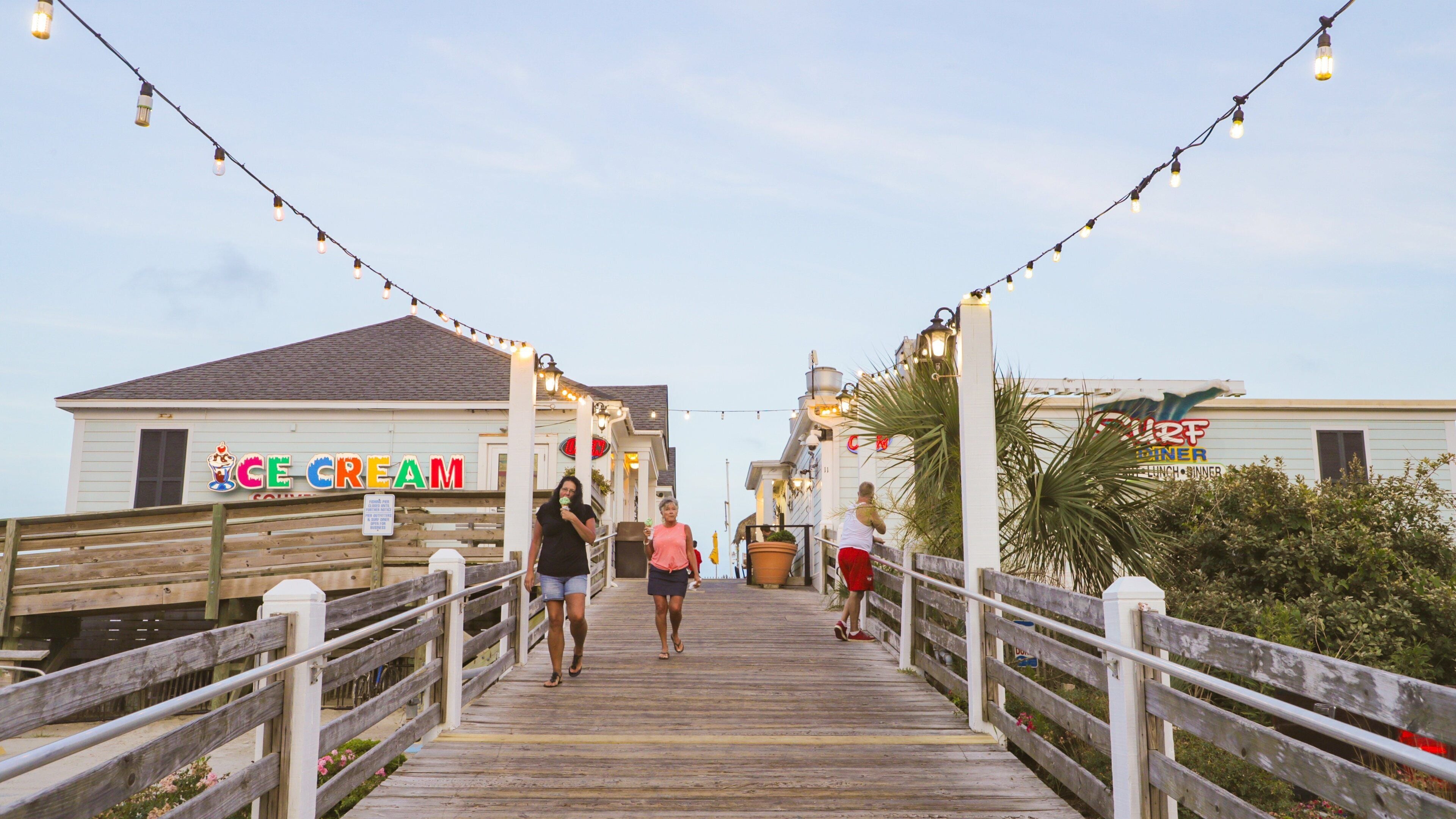 A wooden boardwalk with string lights, leading to a building with an 'ICE CREAM' sign.