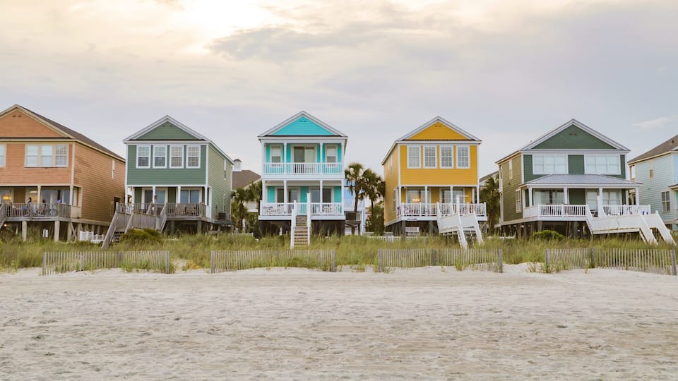 A row of colorful beach houses with wooden decks and railings.