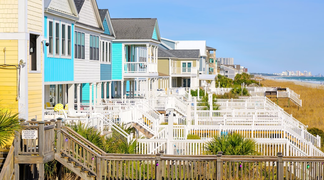 Colorful waterfront homes along the grassy dunes of the Atlantic Ocean with the Myrtle Beach skyline in the distance, in Surfside Beach, South Carolina.