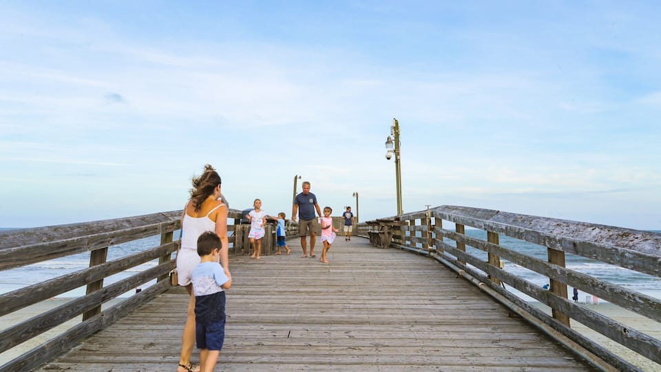 A wooden pier extending into the ocean with people walking along it.
