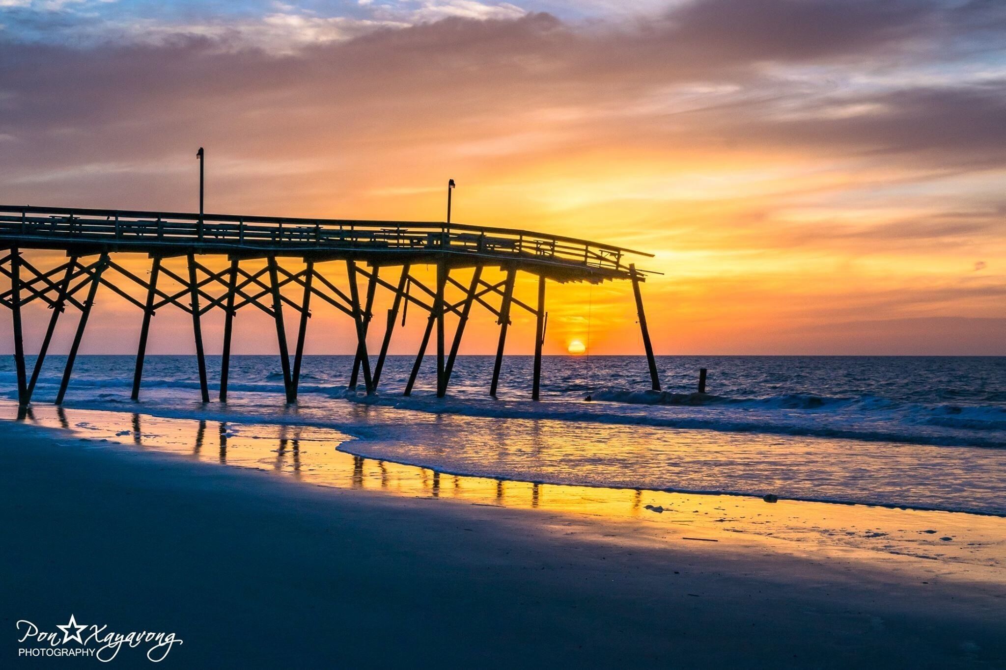 A pier extending into the ocean at sunset.