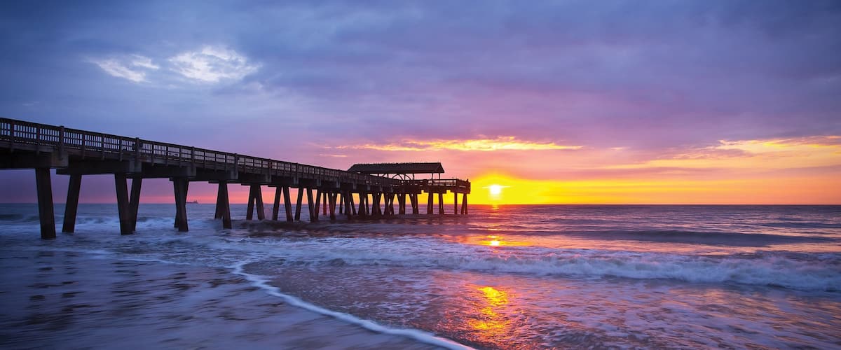 A pier extending into the ocean at sunset.