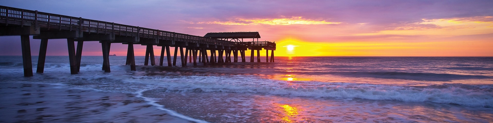 A pier extending into the ocean at sunset.