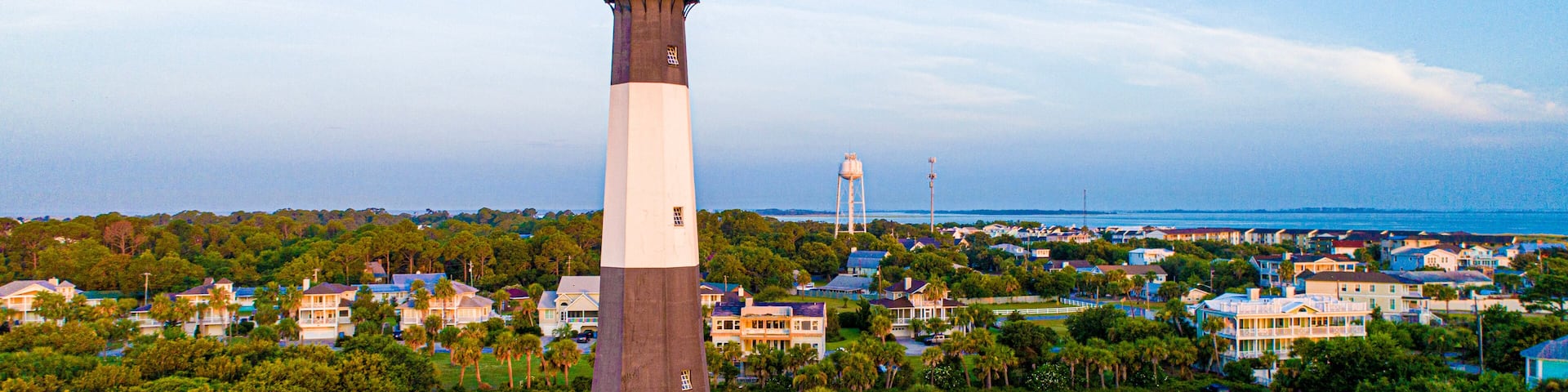 A lighthouse, a water tower, and a residential area with houses and greenery.