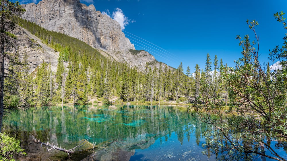 Ein Bergsee mit klarem türkisblauem Wasser, umgeben von dichtem Grünwald und felsigen Klippen.