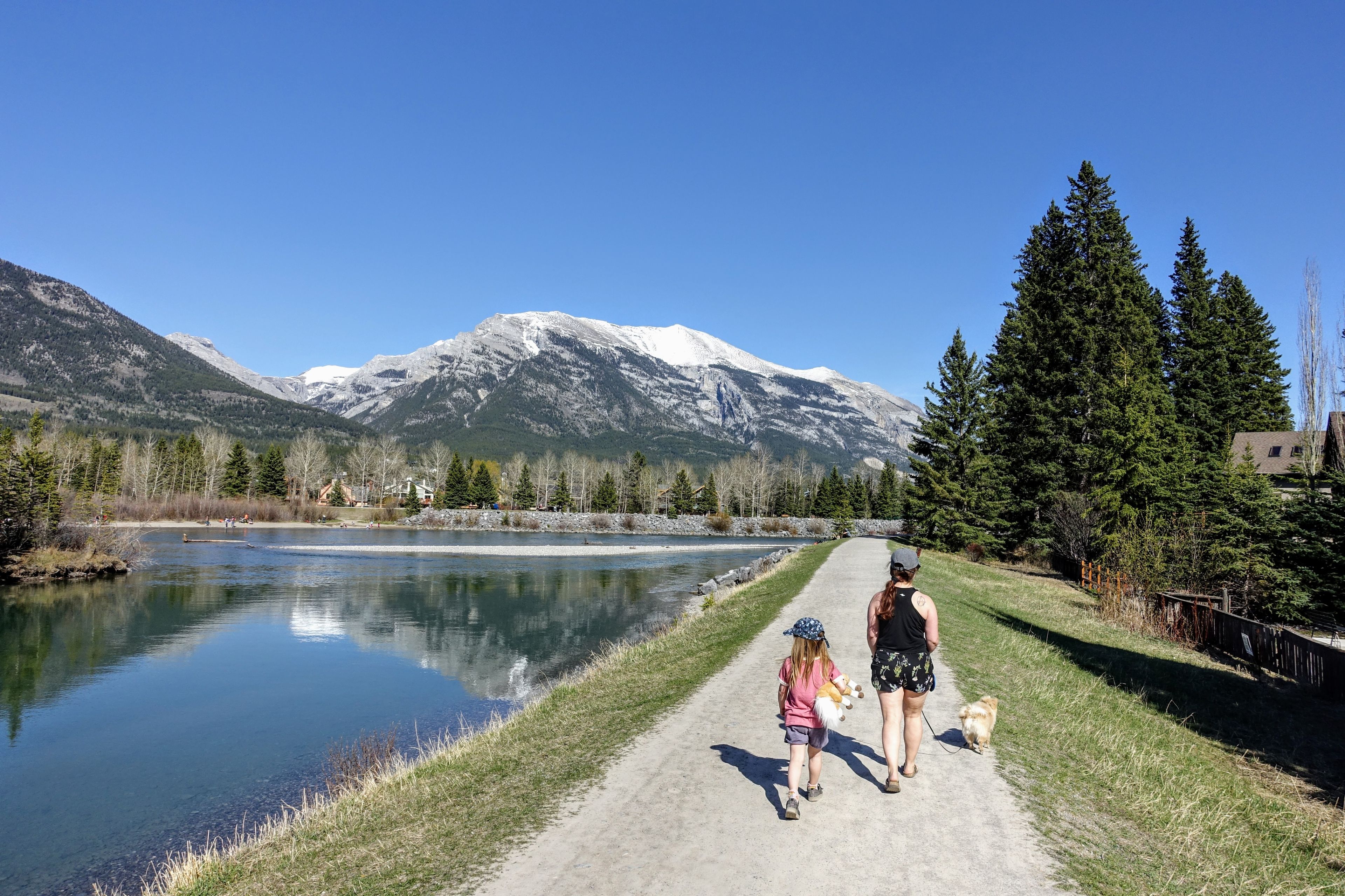 A mother and daughter going for a walk with their dog along the Bow River trails in Canmore, Alberta,  Canada on a beautiful sunny summer day.